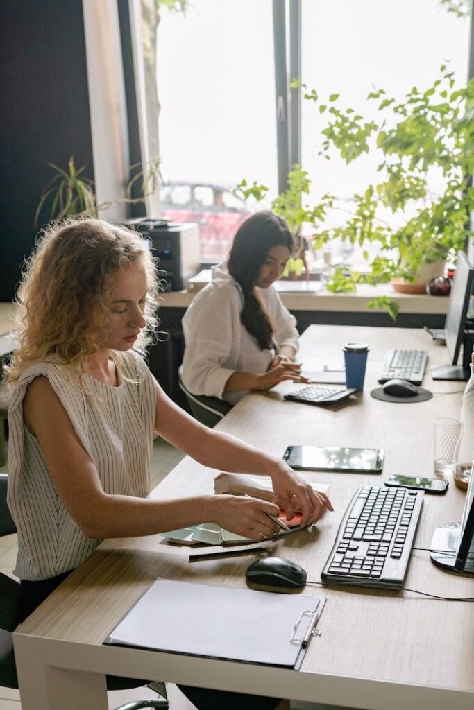 Crafting Captivating Headlines: Your awesome post title goes here Two women focused on work in a bright, plant-filled office space.